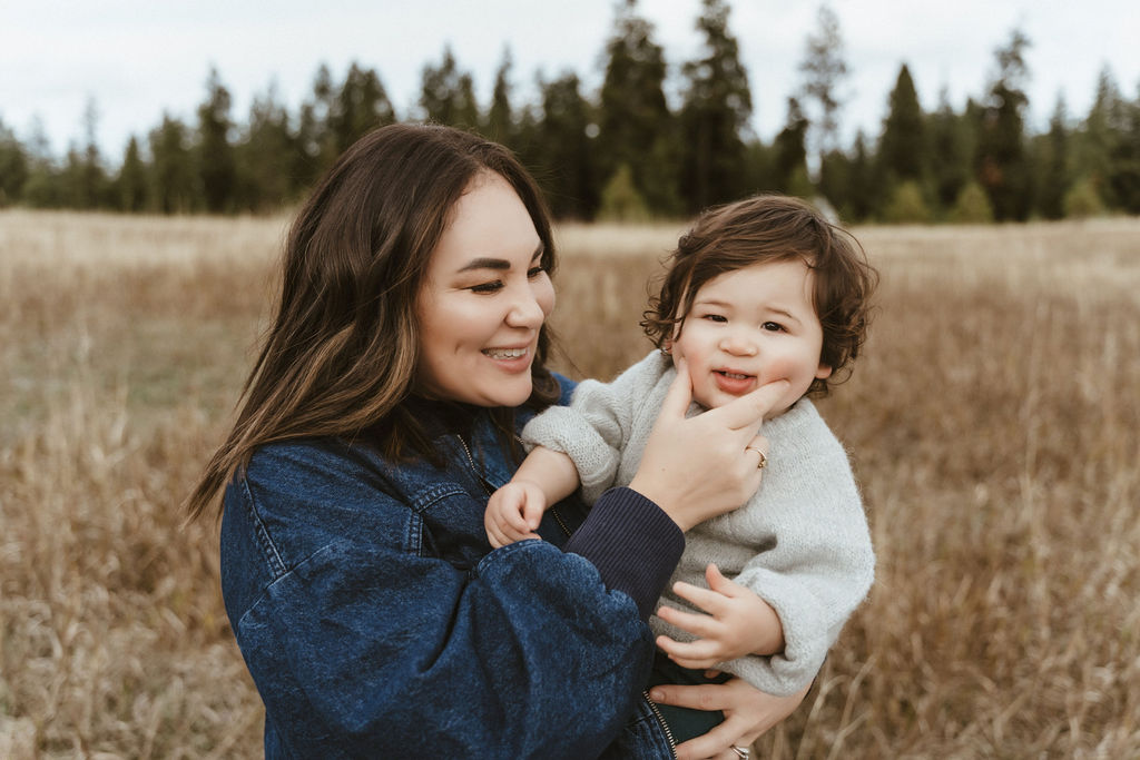 Mom happily squeezing her baby boy's cheeks in a family photo session with Sophie Grace Photography