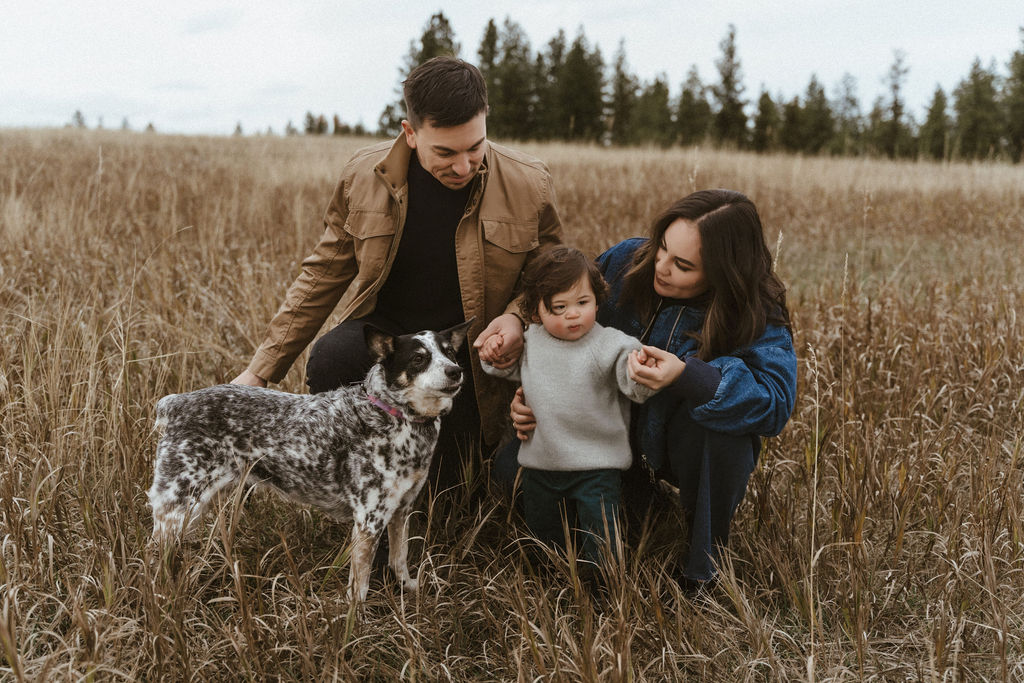 A sweet photo of mom and dad admiring their son, along with their family dog, Stevie, in a Spokane WA family photoshoot with Sophie Grace Photography. 