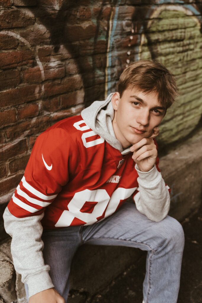 Urban High School Boy wearing red football jersey outfit with Sophie Grace Photography