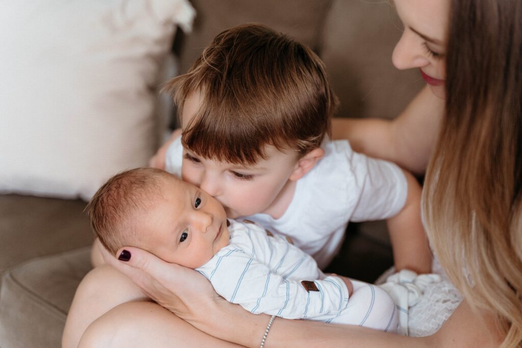big brother kissing his new baby brother in a relaxing in home session with sophie grace photography in spokane wa