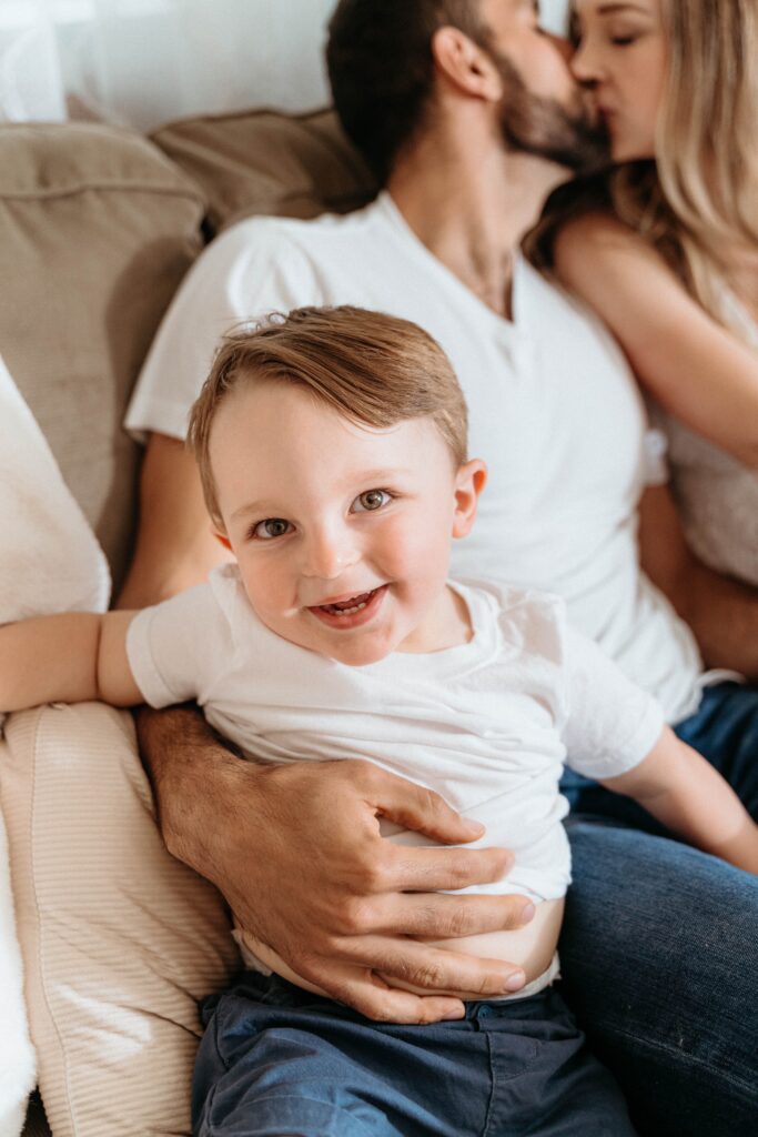 laughing toddler held by dad in a relaxing in home newborn session with sophie grace photography in spokane wa