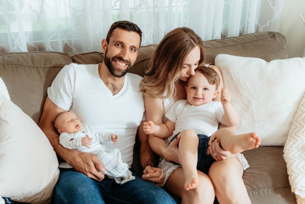 Parents holding their newborn together with their toddler during a relaxed newborn photography session in their Spokane home