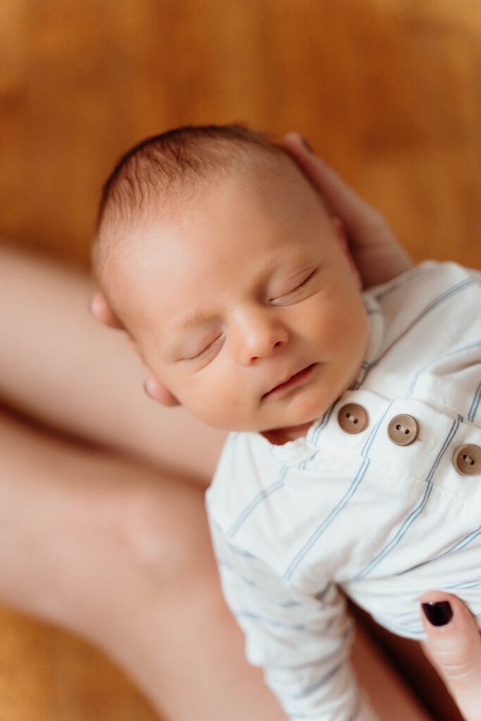 Cute close up of the baby sleeping while mom is holding him in a relaxing newborn session with sophie grace photography in spokane wa