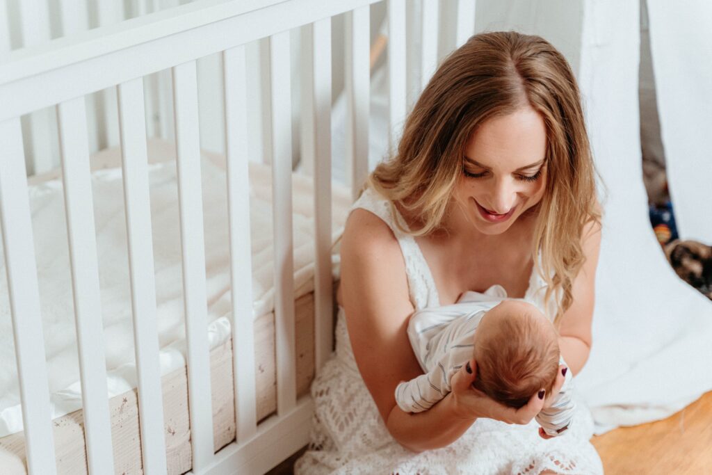 Mom holding her new baby in a relaxing in home newborn session in spokane wa with sophie grace photography