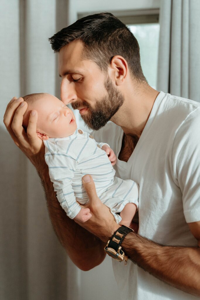 Dad holding new baby in a relaxing in home newborn session with sophie grace photography in spokane wa